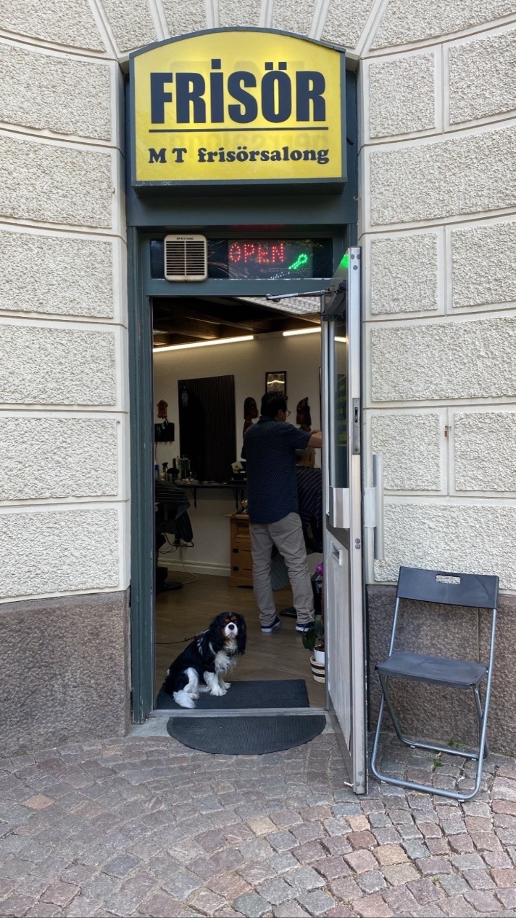 Entrén till MT Hair på Linnégatan 31, gul skylt med texten Frisör och dörren öppen