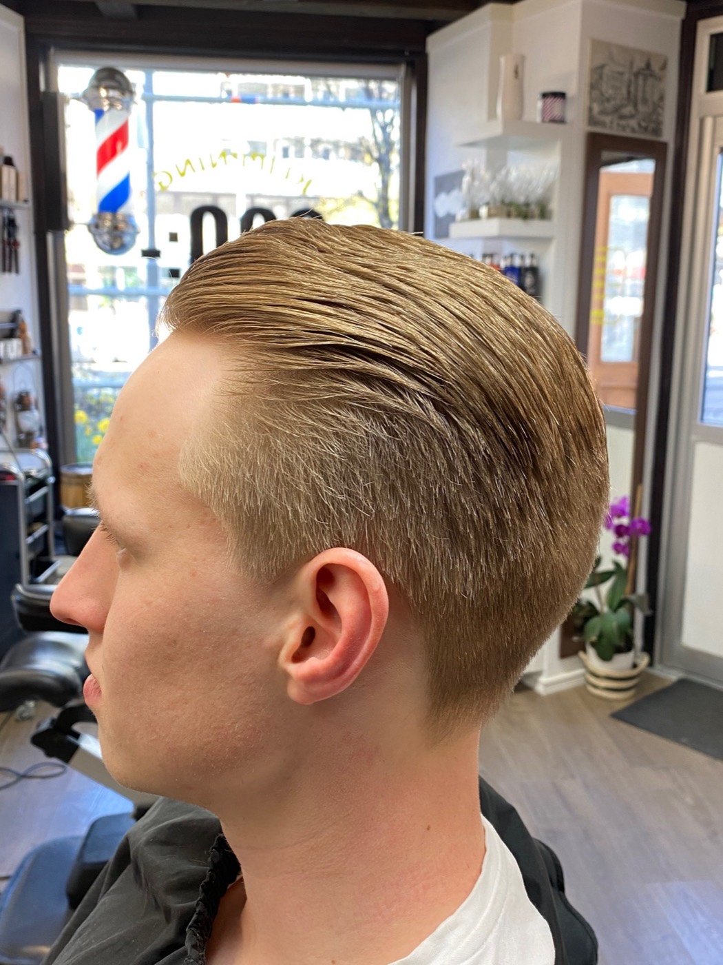 Klassisk bakåtkammad klippning, barberstången syns i fönstret